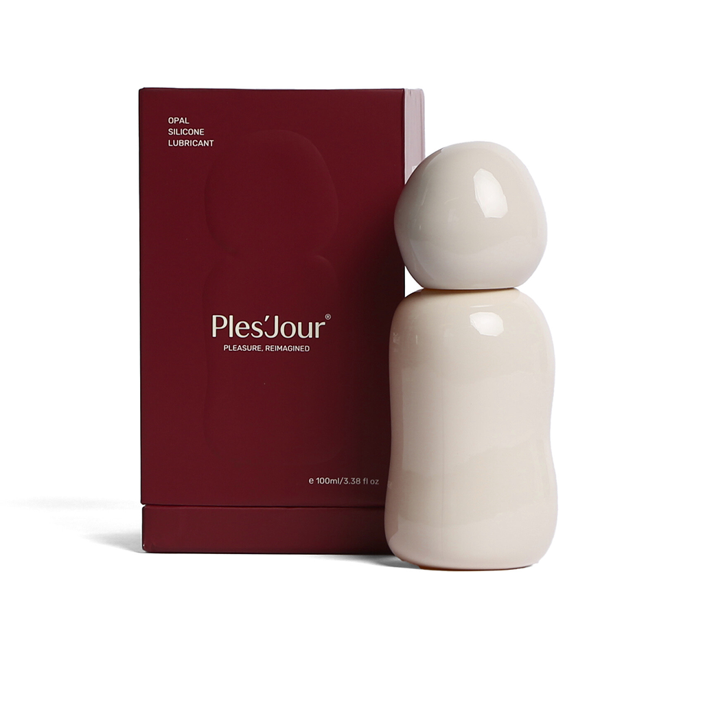 Ples’Jour Opal silicone lubricant in sculptural glass bottle beside burgundy box, representing luxury sexual wellness and intimacy.