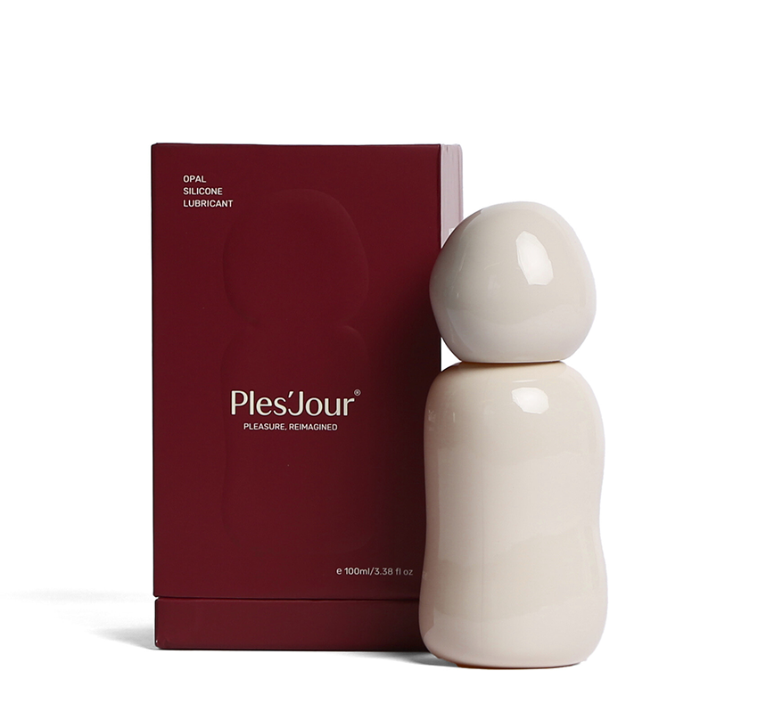 Ples’Jour Opal silicone lubricant in sculptural glass bottle beside burgundy box, representing luxury sexual wellness and intimacy.