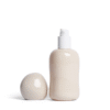Minimalist cream-colored Opal lubricant glass bottle with rounded sculptural design and pump top, with the lid sitting beside.