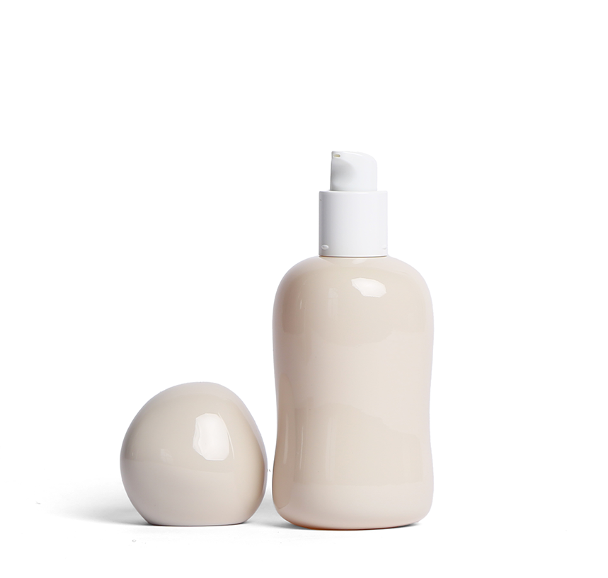 Minimalist cream-colored Opal lubricant glass bottle with rounded sculptural design and pump top, with the lid sitting beside.